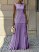 Woman wearing a sleeveless boat neck maxi dress with a knife-pleated drop-waist skirt