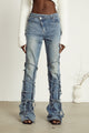 Light wash blue jeans with layered strap details and tie-up cuffs on the lower leg