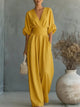 Woman wearing a wide-leg jumpsuit with a wrap V-neck bodice, puff sleeves and a gathered waistband