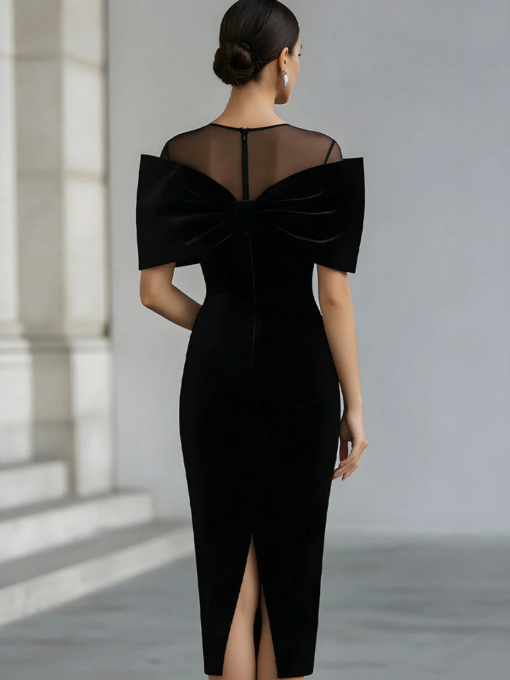 Black velvet midi dress with sheer neckline and oversized bow
