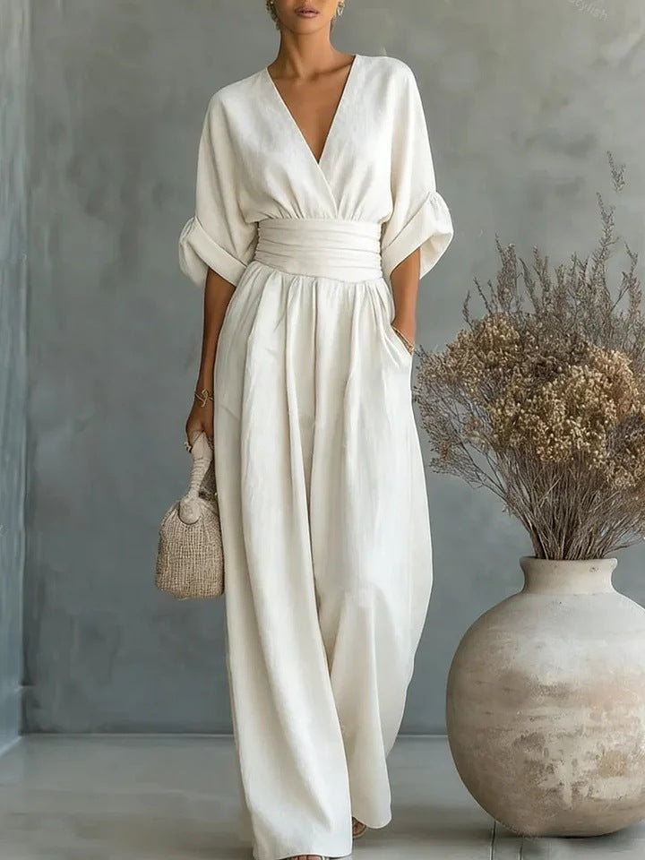 Woman wearing a wide-leg jumpsuit with a wrap V-neck bodice, puff sleeves and a gathered waistband