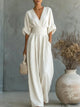 Woman wearing a wide-leg jumpsuit with a wrap V-neck bodice, puff sleeves and a gathered waistband