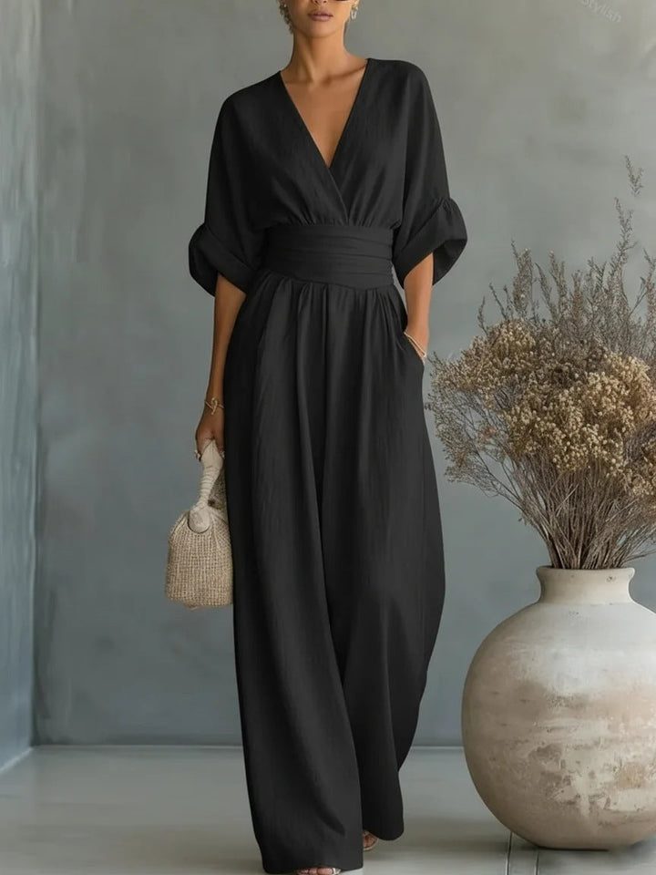 Woman wearing a wide-leg jumpsuit with a wrap V-neck bodice, puff sleeves and a gathered waistband