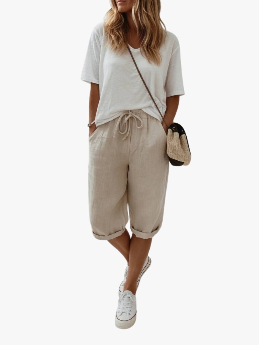 Women's beige bermuda shorts with cuffed hems and drawstring waist, paired with white t-shirt and white sneakers