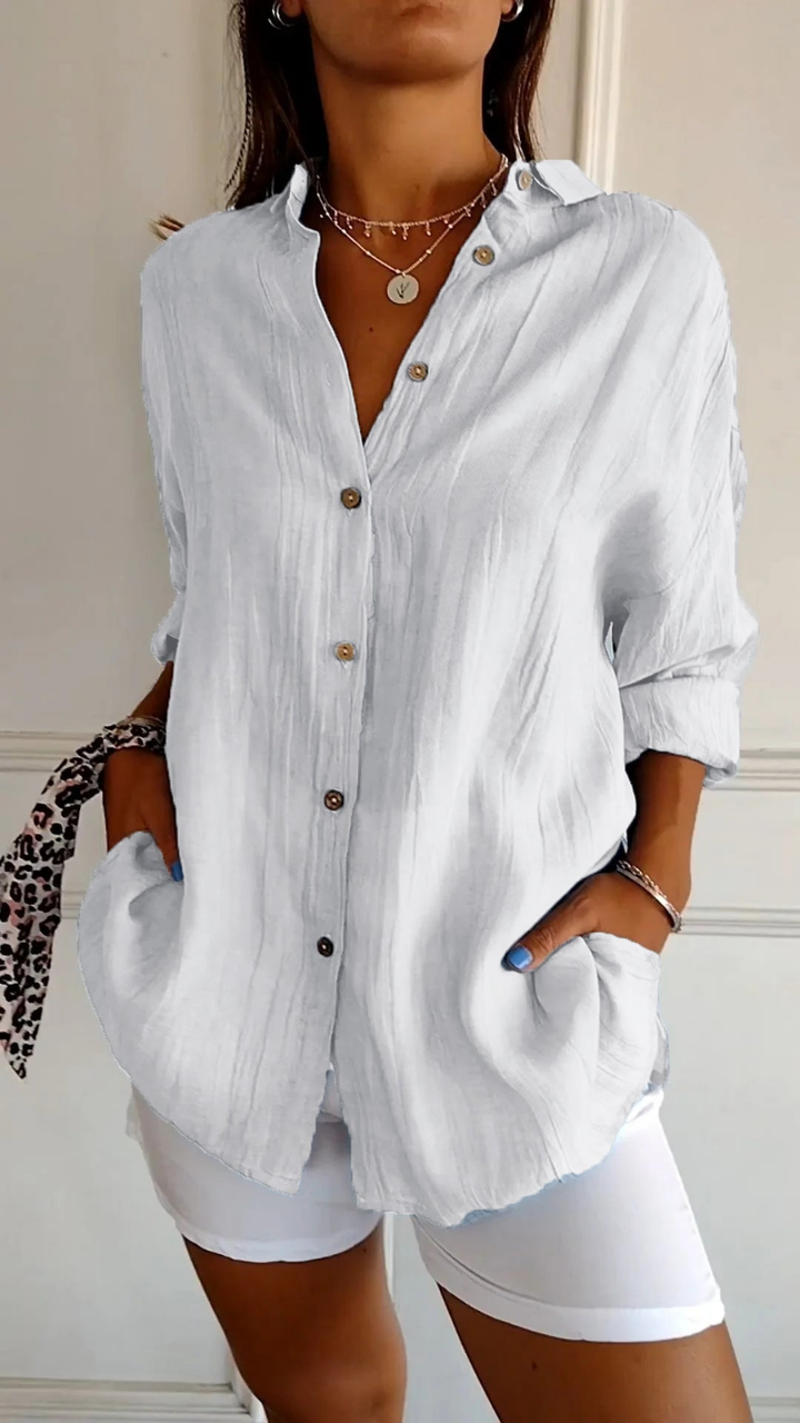 Women's oversized button-down collared shirt in blue, worn with white shorts