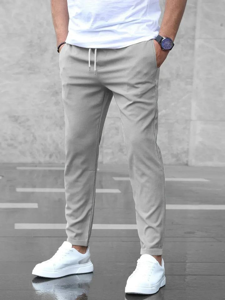 Men's slim-fit jogger pants in grey and olive green, shown with drawstring waist and tapered leg