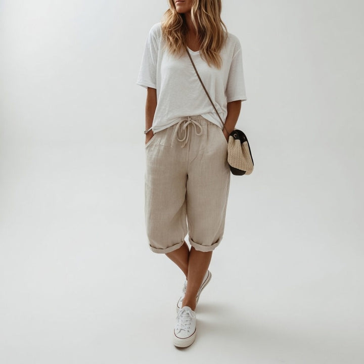 Women's beige bermuda shorts with cuffed hems and drawstring waist, paired with white t-shirt and white sneakers