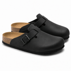 Unisex Positano clog mule with buckle strap, cork insole and black padded sole, shown in taupe and black.