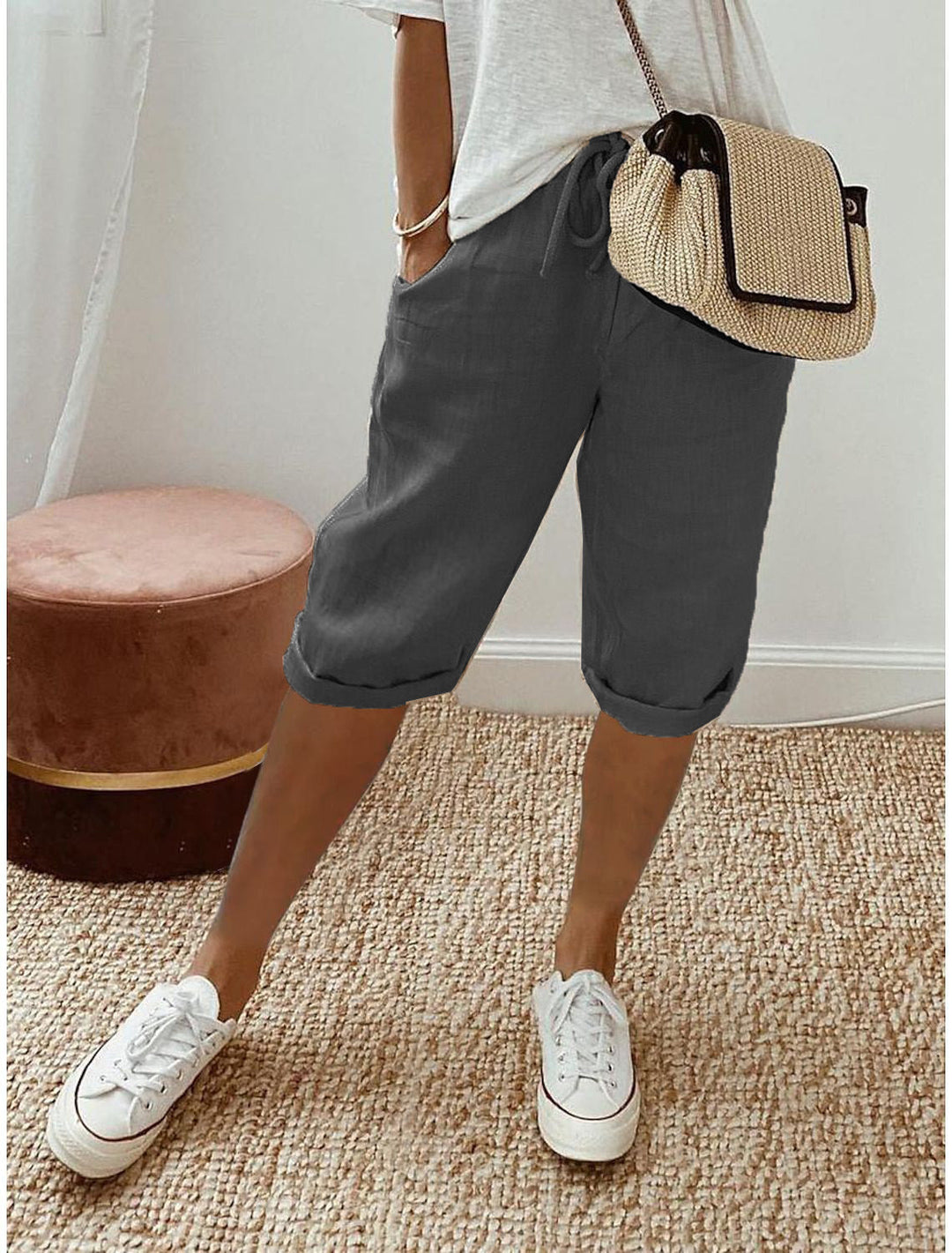 Women's beige bermuda shorts with cuffed hems and drawstring waist, paired with white t-shirt and white sneakers