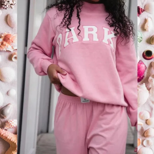 Woman wearing a pink cropped graphic sweatshirt and matching shorts set