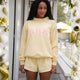 Woman wearing a pink cropped graphic sweatshirt and matching shorts set