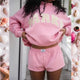 Woman wearing a pink cropped graphic sweatshirt and matching shorts set