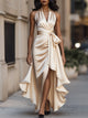Woman wearing a halterneck maxi dress with a tie waist, high split and cascading ruffle hem