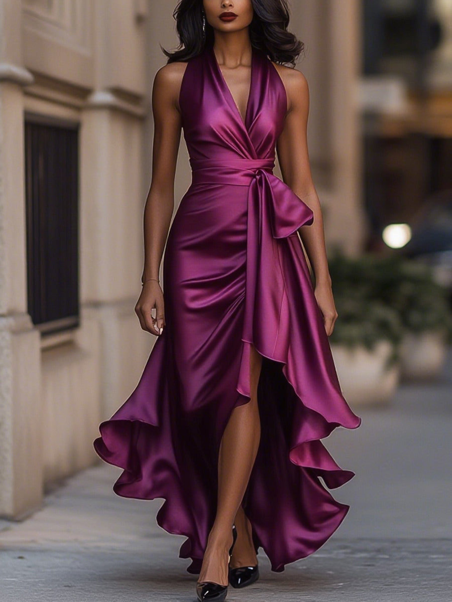 Woman wearing a halterneck maxi dress with a tie waist, high split and cascading ruffle hem