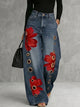 Women's wide leg blue jeans with red floral print and gold grommet details, high waisted
