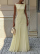 Woman wearing a sleeveless boat neck maxi dress with a knife-pleated drop-waist skirt