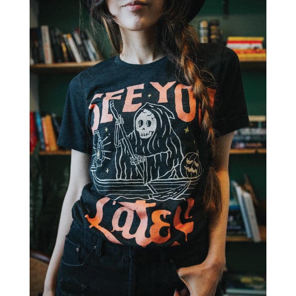 Black crew neck t-shirt with orange and cream graphic print of hooded figure in boat